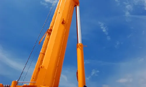 A telescopic crane boom extended against the sky — representative of the heavy-lift equipment used around steel production, not a mill interior
