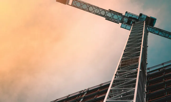 Low-angle view of a tower crane against a dramatic sky