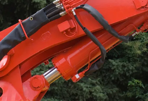 A hydraulic cylinder and its hose routing mounted on a painted excavator boom, in service