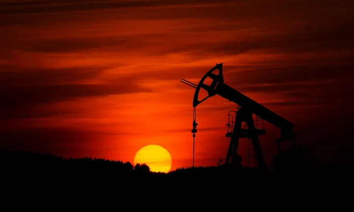 Pumpjack working against a red sunset in an oil field