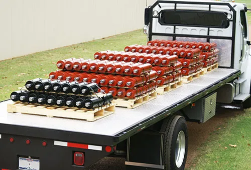 A flatbed truck loaded with WestCraft's own painted hydraulic cylinders, racked and ready to ship